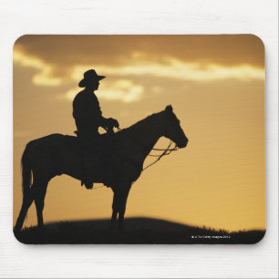 Silhouette of cowboy on horseback at sunset or mouse pad