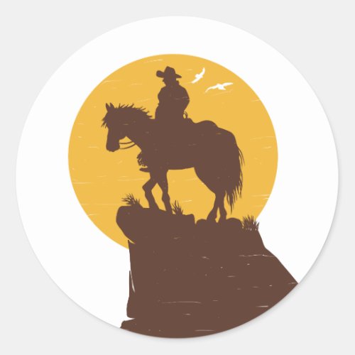 Silhouette of cowboy riding horse at sunset classic round sticker