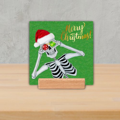 Silly Skeleton Holding Ornaments in Santa Hat Gold Holder