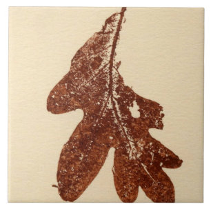 Single oak leaf nature printed in brown ink on tan ceramic tile