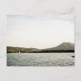 Small ship sailing on a lake at the afternoon postcard