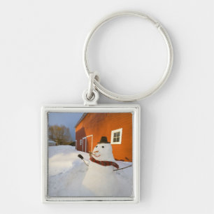 Snowman in front of red barn in Columbia Falls Keychain