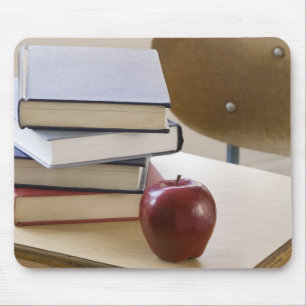 Stack of books, apple, and school desk mouse pad