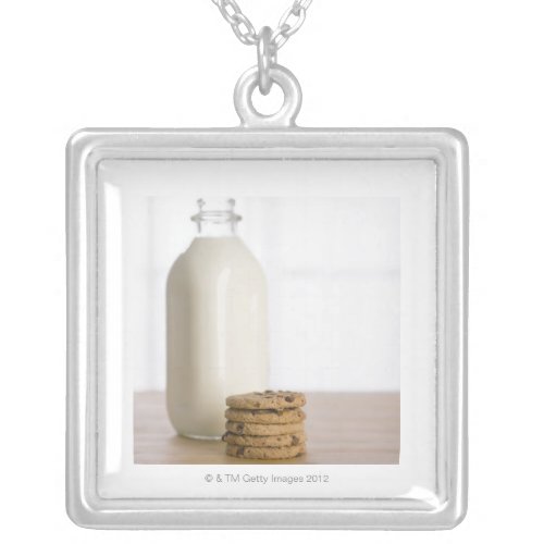 Stack of chocolate chip cookies milk in a glass silver plated necklace