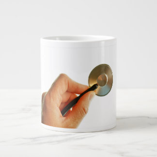 Stethoscope in a hand for a hospital atmosphere. giant coffee mug