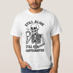 Still Alive Still Caffeinated. Skeleton Coffee T-Shirt<br><div class="desc">Bold, edgy, and full of caffeine fueled humor - this black and white T-shirt design features a goth vintage style skeleton holding a steaming cup of coffee, paired with the witty quote “Still Alive, Still Caffeinated.” Perfect for Halloween, coffee lovers, night owls, and anyone embracing life with a dark twist...</div>
