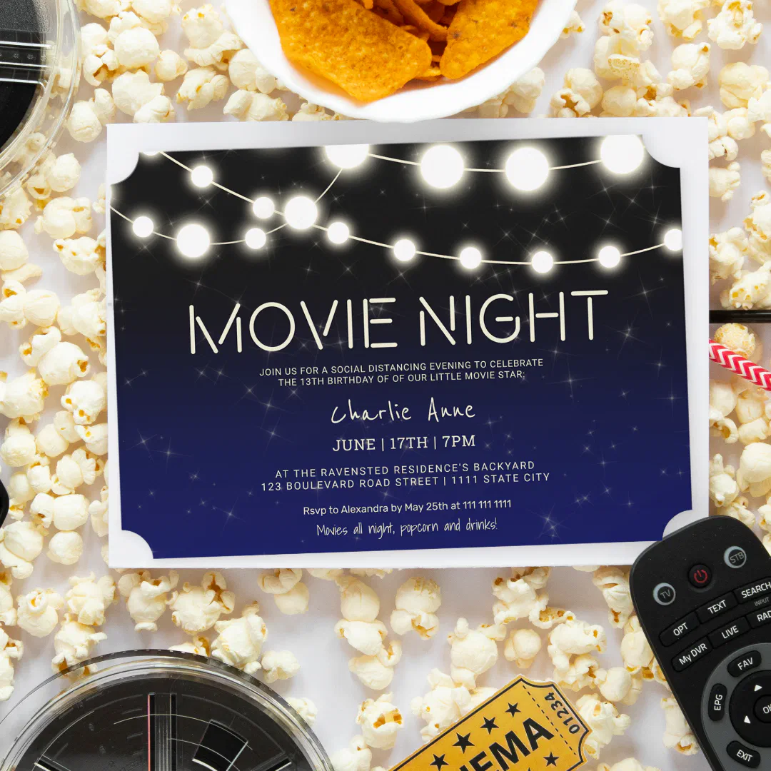 Navy blue backyard movie night birthday invitation with glowing string lights and a starry sky design, displayed on a bed of popcorn.