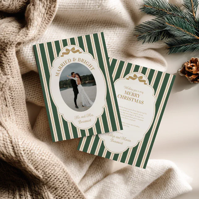 A green and gold striped holiday card resting on a beige blanket next to a pine cone and some fir tree sprigs.