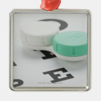Studio shot of contact lens case on eye chart metal ornament