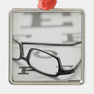Studio shot of eyeglasses on eye chart metal ornament