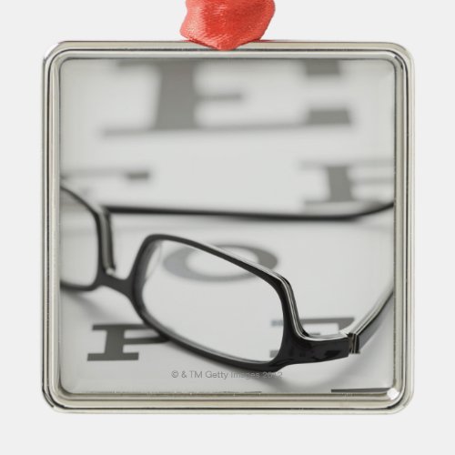 Studio shot of eyeglasses on eye chart metal ornament