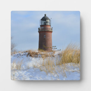 Sturdy Lighthouse on a Rocky Coast in Winter Plaque