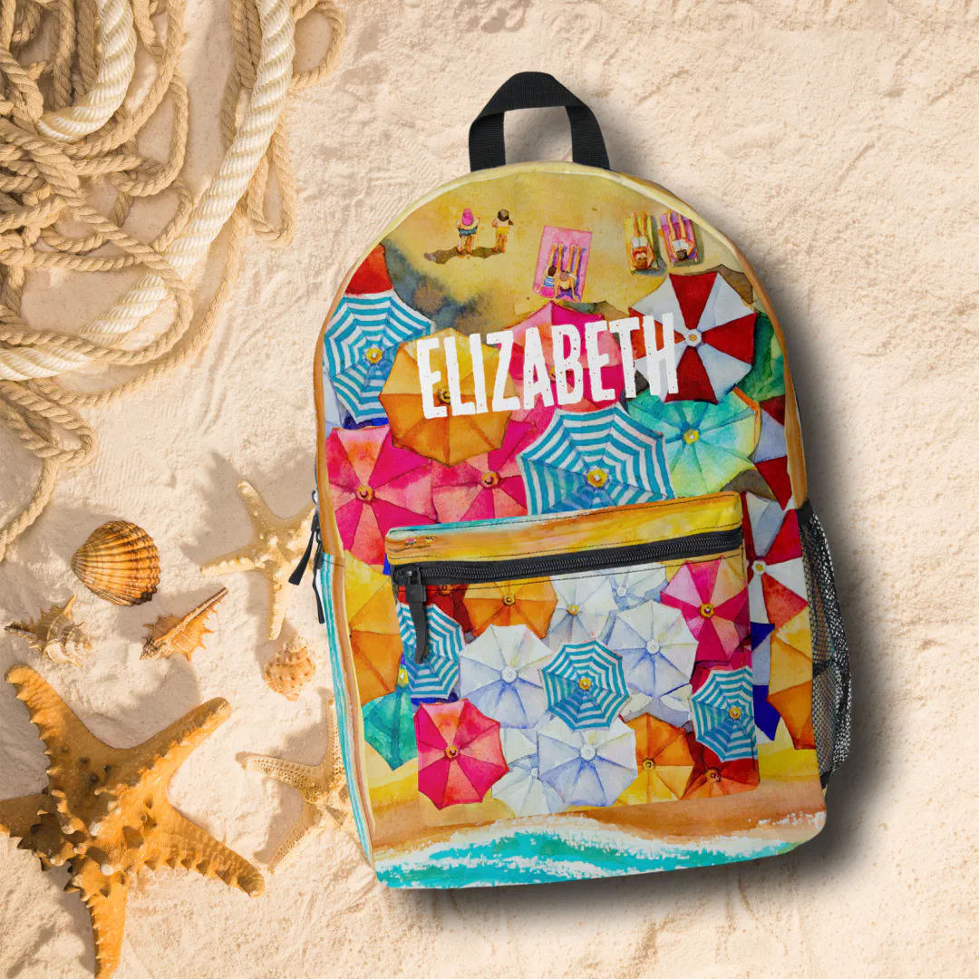 A backpack with blue, white, yellow, red and green umbrellas printed on it with a small image of a beach with sunbathers. In the background there's sand, rope and brown starfish.