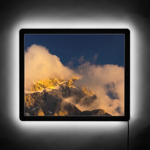 Sun lit mountains covered by clouds LED sign