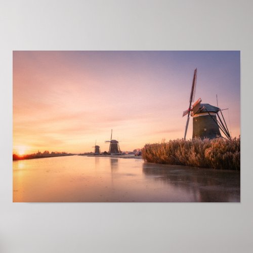 Sunrise over frozen river with windmills and reeds poster