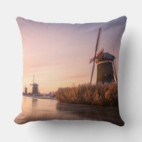 Sunrise over frozen river with windmills and reeds throw pillow