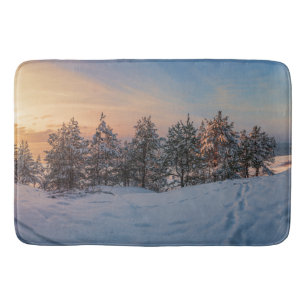 Sunset over frozen snowy forest near sea bath mat