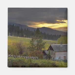 Sunset sky over vineyards and historic log cabin magnet