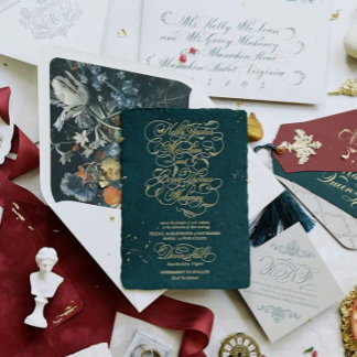A refined arrangement of wedding invitations in deep jewel tones and gold foil details. Organic motifs and classical serif typography create an elevated, museum-quality feel. Layered envelopes and textured paper add depth. The palette communicates timeless craftsmanship.