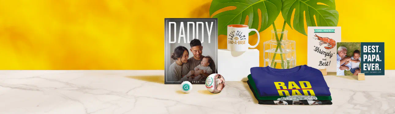 Father's Day gift assortment from Zazzle — photo cards, mugs and a folded tee on a sunny marble counter