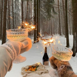 Two people in mittens hold glowing string-light-wrapped drinks in a snowy forest at dusk. The tone is magical and wintry.