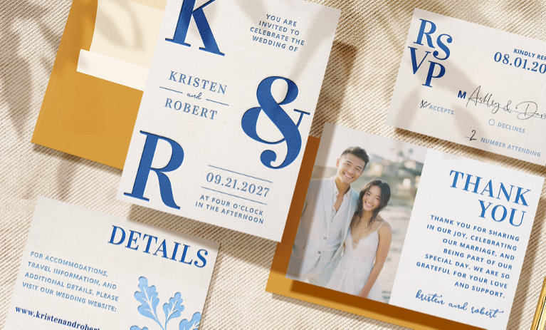 Elegant letterpress wedding stationery suite with blue text on textured paper, featuring invitations, RSVP, and a photo thank-you card over a linen background with shadows.