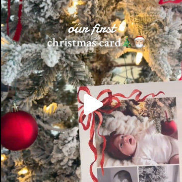 A video frame showing a photo card placed in front of a lit Christmas tree with a play button overlay. Warm, festive, and engaging style.