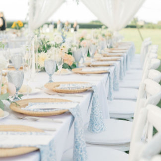 A breezy outdoor table setting featuring soft, coastal blues and crisp white linens. Natural light and minimal décor create an airy, serene mood. Subtle variations of blue add depth. The scene embodies relaxed beach elegance with a modern twist.