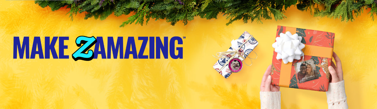 Festive yellow backdrop with pine garland on top. Bold text says ‘Make Zamazing.’ Two cheerful gifts sit below, each topped with a custom photo ornaments. One of a cute dog, the other of a smiling couple. Cozy hands hold the larger box wrapped in a pattern tigers and Christmas trees.