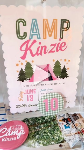 A pastel "Camp"-themed party invitation suite with tents and pine trees, flat-laid over greenery and matching favors. Playful, outdoorsy, kid-party mood. 