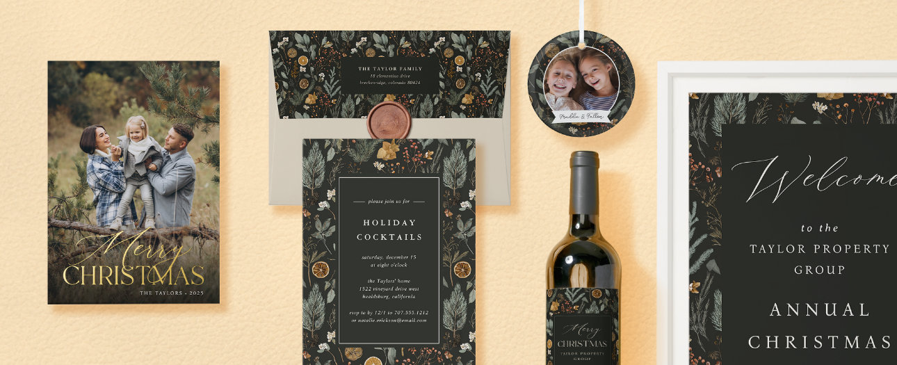 A coordinated holiday stationery suite featuring dark floral invitations, a holiday photo card, a wine bottle with a matching label, and a “Welcome” sign, all in deep green, black, and gold tones with botanical motifs.
