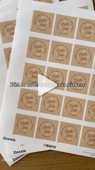 A sheet of 'North Pole' delivery stickers in kraft brown and white, laid flat on wood. Playful, festive, Santa-prep mood.