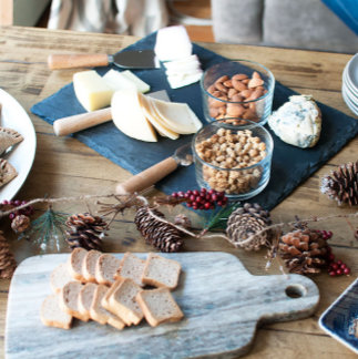 A close-up of a hand lighting a seasonal bonfire, with pinecones and winter greenery in view. The aesthetic is earthy and spiritual, celebrating the return of light.