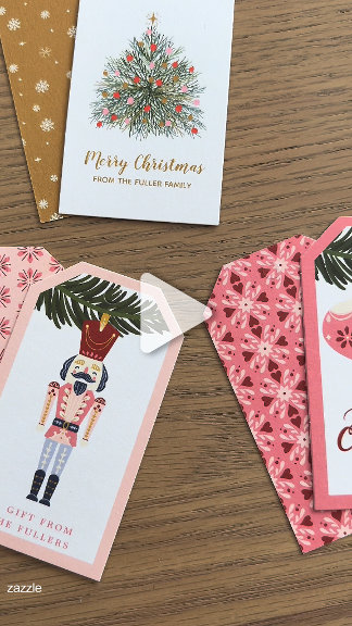 Nutcracker and floral holiday gift tags in pink, gold, and cream, fanned on wood. Elegant, whimsical, gift-wrapping mood.