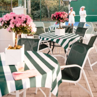 A sporty, celebratory outdoor tablescape styled with tennis-inspired elements. Green-and-white stripes, rackets, and playful florals create an upbeat preppy vibe. Bright lighting and open space give it a breezy feel. It blends athletic energy with chic event styling.