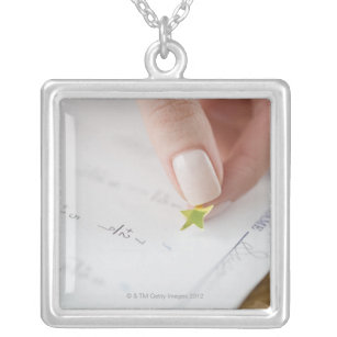 Teacher affixing gold star to math worksheet silver plated necklace