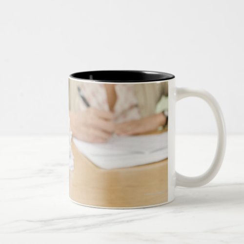 Teacher grading papers with apple in foreground Two_Tone coffee mug