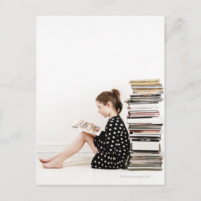Teenage girl reading comic strip by pile of postcard (Front)