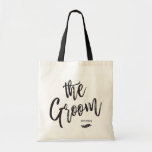 The Groom | Script Style Custom Name Wedding Tote Bag<br><div class="desc">Make the groom feel extra appreciated with this special custom name canvas style tote bag.
 
 It features the words "the groom" in an elegant script style text. Underneath this is a spot for his name or initials above a leaf ornamental.</div>