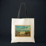 The Hamptons Beach Vintage Travel Tote Bag<br><div class="desc">This Greetings From The Hamptons vintage postcard design features a sandy beach with a beautiful turquoise ocean water and above the sea,  a blue sky with billowy white clouds. In vintage travels style.</div>