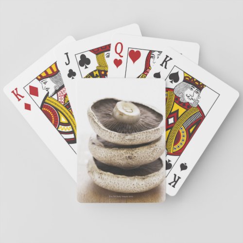 Three flat mushrooms in pile on wooden board playing cards