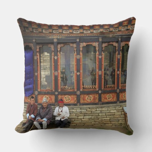 Three men sit on a bench at the Memorial Chorten Throw Pillow