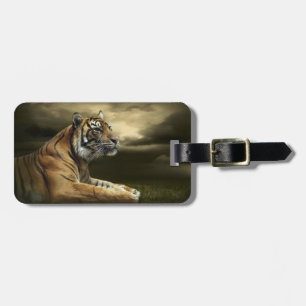Tiger looking and sitting under dramatic sky luggage tag