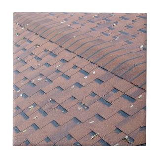 Top view of brown roof shingles with a few autumn ceramic tile