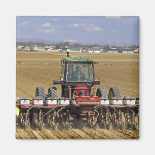 Tractor pulling a seed corn planter. magnet