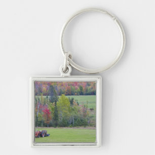 Tractor with hay bale in green field with keychain