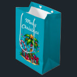 Tropical Palm Tree Merry Christmas Medium Gift Bag<br><div class="desc">Gift bag with a seasonal holiday image. A tropical palm tree decorated in festive lights with a star on top. A giant red and white candy cane sticking out of the sand. Christmas presents under the tree. Whimsical and fun.</div>
