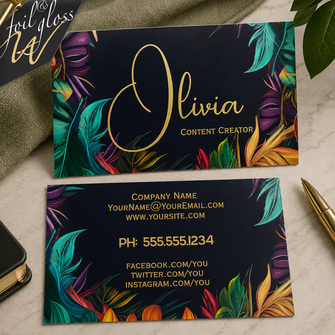 Tropical aqua, purple, yellow and green palm leaves are printed on a black business card with gold foil text on the front and back. There's a neutral green tone in the background.