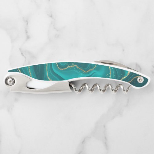 Turquoise liquid marble background with gold waiters corkscrew