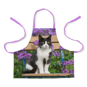 Tuxedo cat sitting on a garden chair with flowers apron